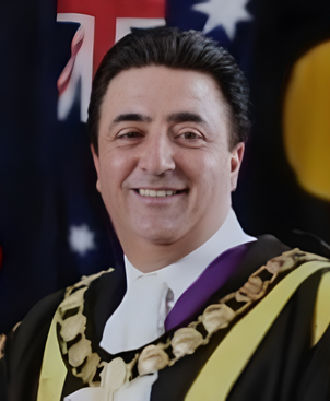 Passport-style portrait of John Chedid, board member, wearing professional attire and smiling confidently.